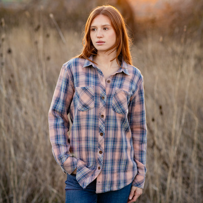 Young woman in Pladra Women's Fireside Flannel–Lily Pink stands outdoors in a dry grassy field, looking to the side.