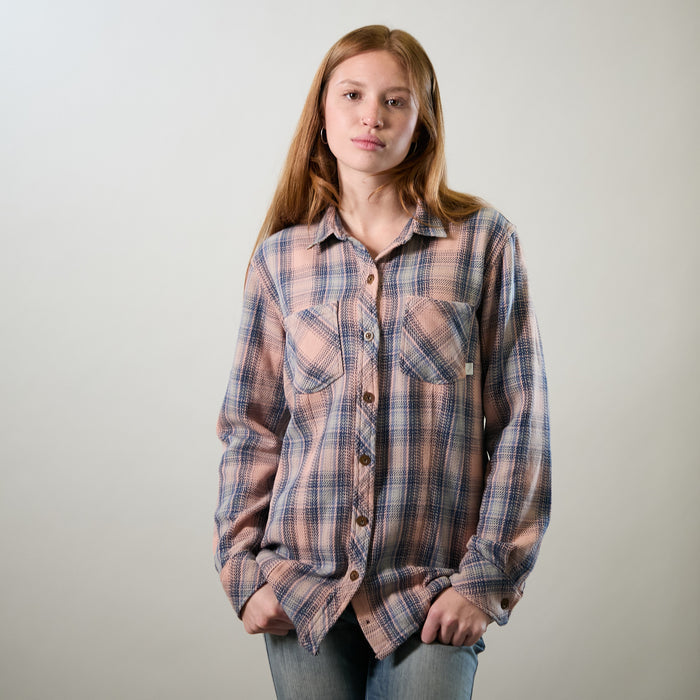 A young woman with long red hair wears the Pladra Women's Fireside Flannel–Lily Pink and jeans against a light background.