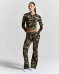 A model wearing a matching camouflage zip-up hoodie and flared sweatpants set, standing against a light gray studio background.