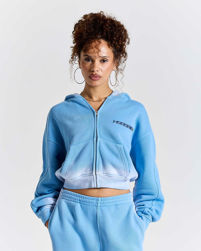 Model wearing a blue ombre zip-up cropped hoodie with Hoodrich logo embroidery.