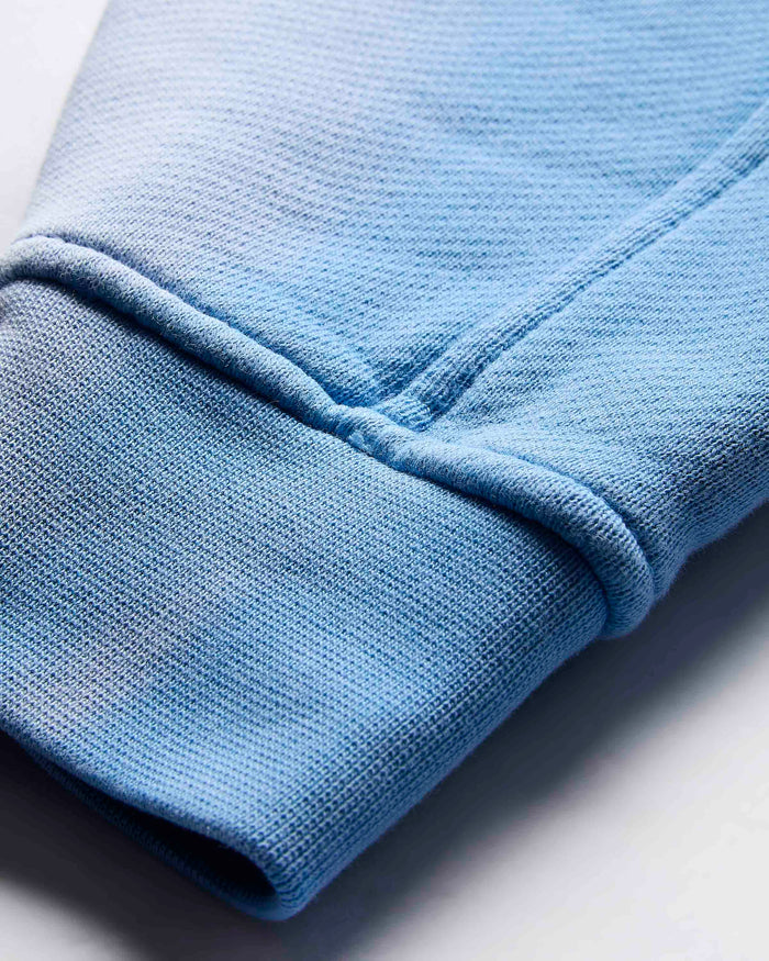 Close-up of the ribbed cuff on the sleeve of the blue cropped hoodie.