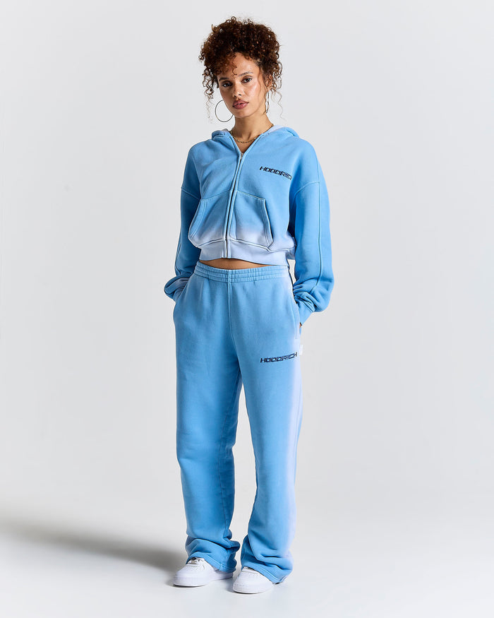 Person wearing a light blue tracksuit with a brand logo on a white background