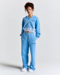 Person wearing a light blue tracksuit with a brand logo on a white background