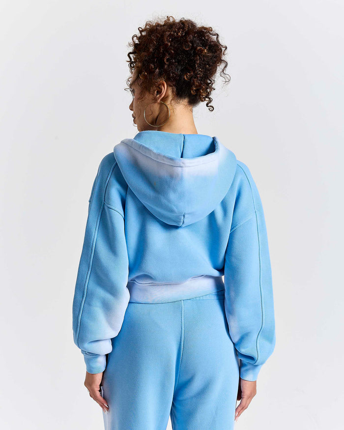 Person wearing a light blue tracksuit on a white background