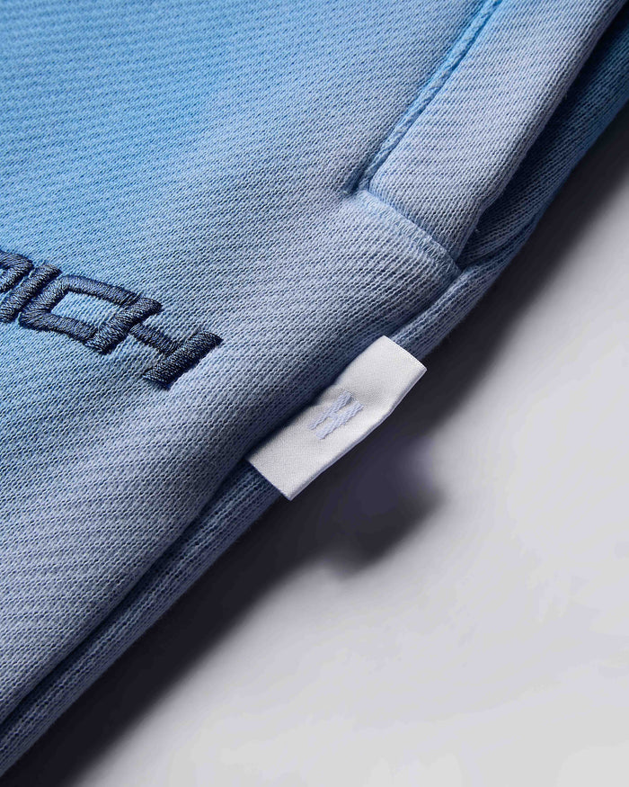 Close-up of a blue garment with a brand label on a light gray background