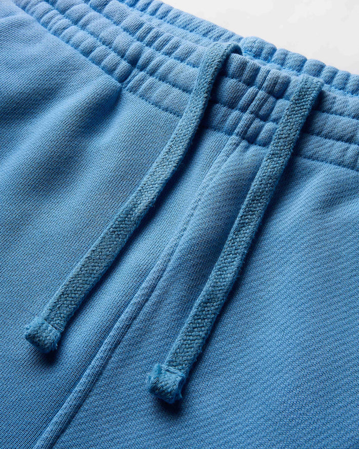 Close-up of blue fleece pants with drawstrings on a light gray background