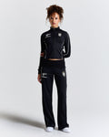 Displays a model wearing the Black 'Hoodrich' branded women's Glide Football Full Tracksuit