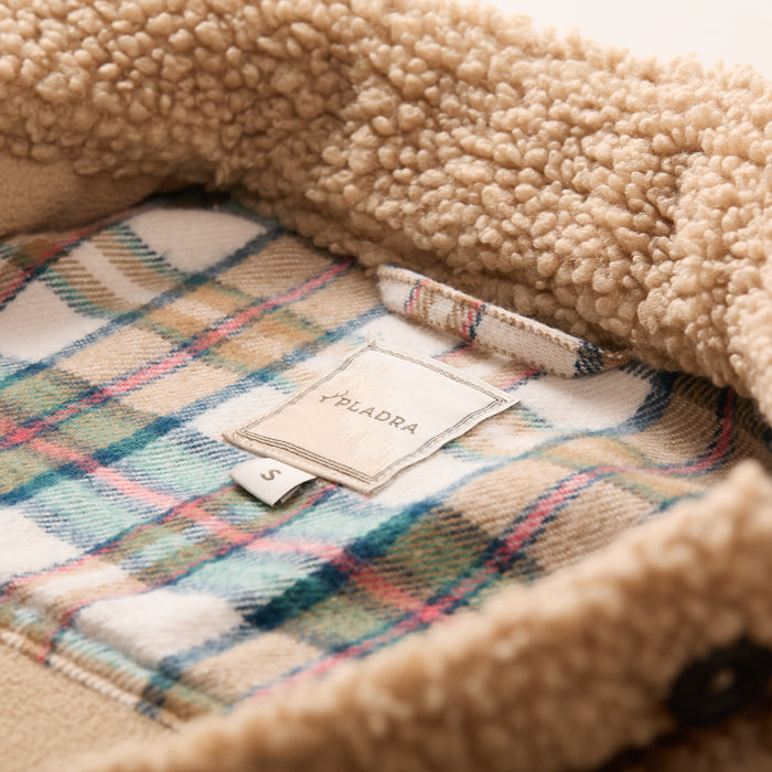 Close-up of a Pladra Women's Headlands Sherpa Shacket label over plaid lining with size S tag in Almond Tan.