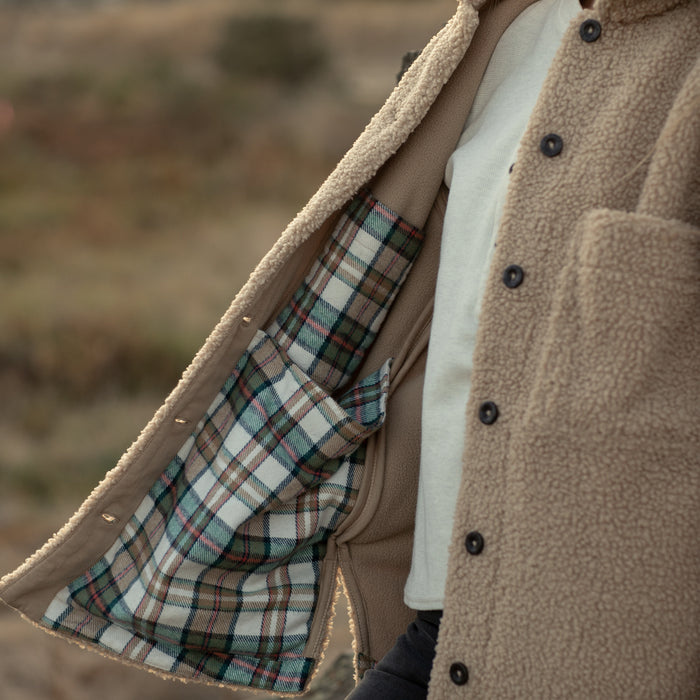 Model in Pladra Women's Headlands Sherpa Shacket–Almond Tan shows off its plaid flannel-lined interior.