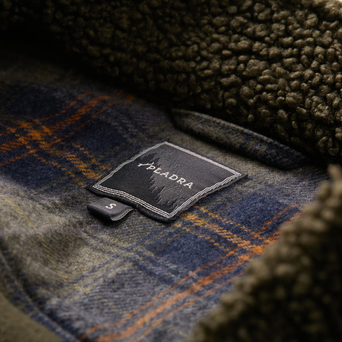 Close-up of Pladra Women's Headlands Sherpa Shacket in Forest Green, size S, on fuzzy brown fabric.