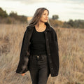Women's Headlands Sherpa Shacket in Onyx Black with plaid flannel lining, worn walking through a dry grassy field.