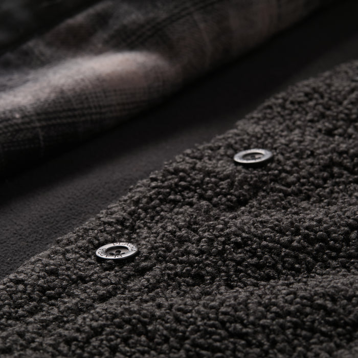 Close-up of the Women's Headlands Sherpa Shacket in Onyx Black, featuring dark textured fleece, two black snap buttons, and a soft plaid flannel lining.