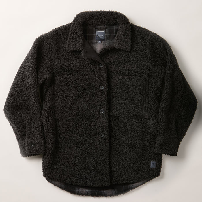 The Women's Headlands Sherpa Shacket in Onyx Black features soft, fluffy fleece, plaid flannel lining, a button-down front, collar, two large chest pockets, and a subtle brand tag on the lower side.