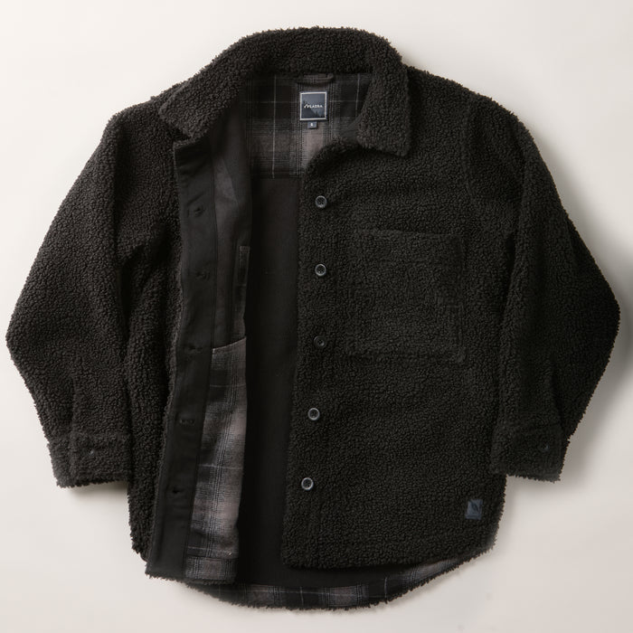 The Women's Headlands Sherpa Shacket in Onyx Black is laid flat on a white background, unbuttoned to display its plaid flannel lining and exterior chest pocket for style.
