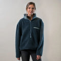 A woman with light brown hair tied back wears a Women's Jenner Sherpa Fleece in Atlantic Blue and dark jeans, standing against a plain light background and looking at the camera with a slight smile.