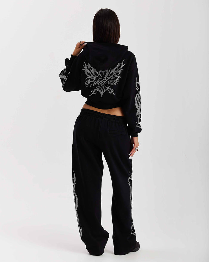 Person wearing a black hoodie and pants with white designs on a white background