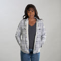 Woman in Pladra Women's Northwood Sherpa Insulated Flannel Jacket in Cloud Grey, over a dark gray shirt and jeans, smiling.