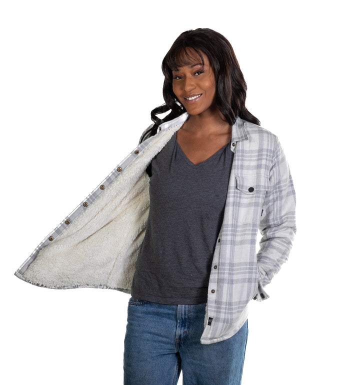 Woman smiling in jeans and a gray shirt, revealing the fuzzy lining of her Pladra Women's Northwood Flannel Jacket in Cloud Grey.
