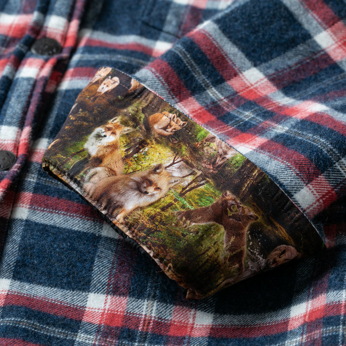 A glasses case with a fox pattern rests on the Women's Northwood Sherpa Insulated Flannel Jacket in Eagle Blue.