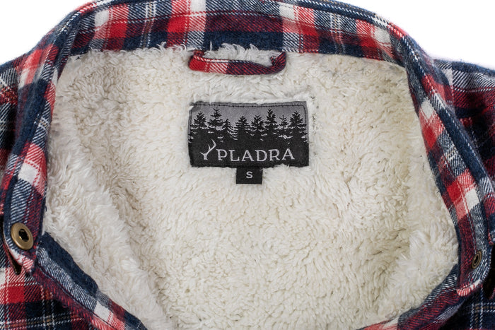 Close-up of the inside collar of the Women's Northwood Sherpa Insulated Flannel Jacket in Eagle Blue, showing soft white fleece lining. A black “PLADRA” label with tree graphics and a size “S” tag are visible.