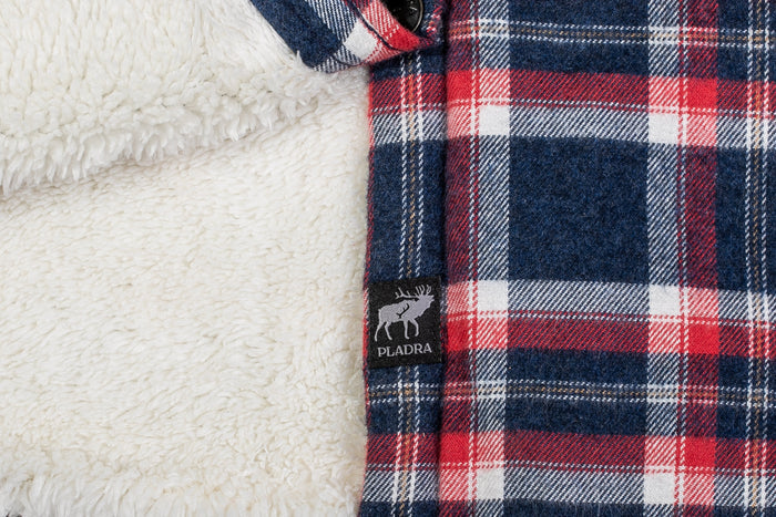 Close-up of the Women's Northwood Sherpa Insulated Flannel Jacket in Eagle Blue, featuring a red, white, and blue exterior and soft white fleece lining. A small PLADRA tag with a moose is visible on the seam.
