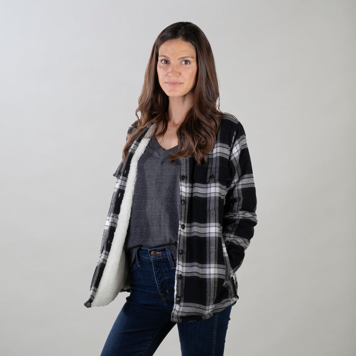 A woman with long brown hair wears the Pladra Women's Northwood Sherpa Insulated Flannel Jacket in RP Onyx Black.