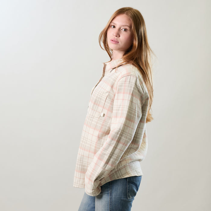 A young woman with long red hair, in jeans and a Women's Relaxed Every Day Elite Flannel Shirt—Lighthouse White, stands sideways and looks at the camera against a plain light background.