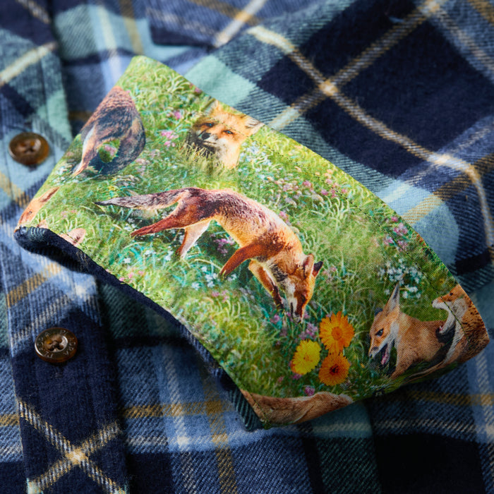 A close-up of the Women's Every Day Flannel Shirt in Bay Blue shows its cuff turned up to reveal a colorful lining with illustrated foxes in a grassy meadow, adding an artful detail to this stylish women's plaid flannel.