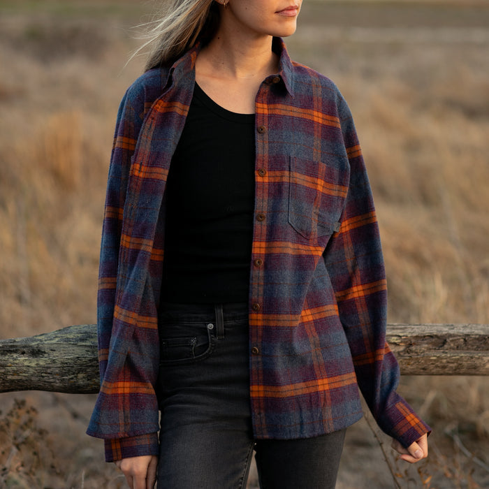 Woman models Pladra Women's Relaxed Every Day Flannel Shirt in Portsmouth Blue Heather by a wooden fence in a field.