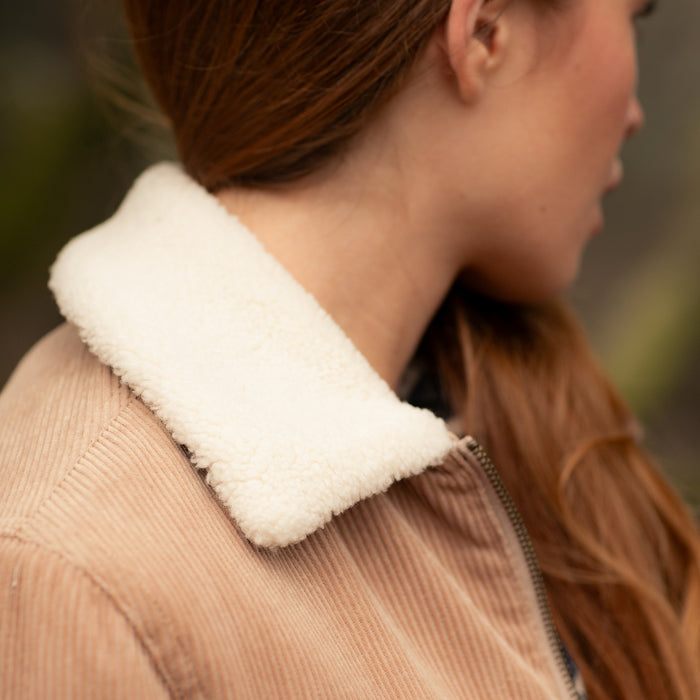 Close-up of a person with long brown hair wearing the Pladra Women's Stinson Jacket in Oak Tan.