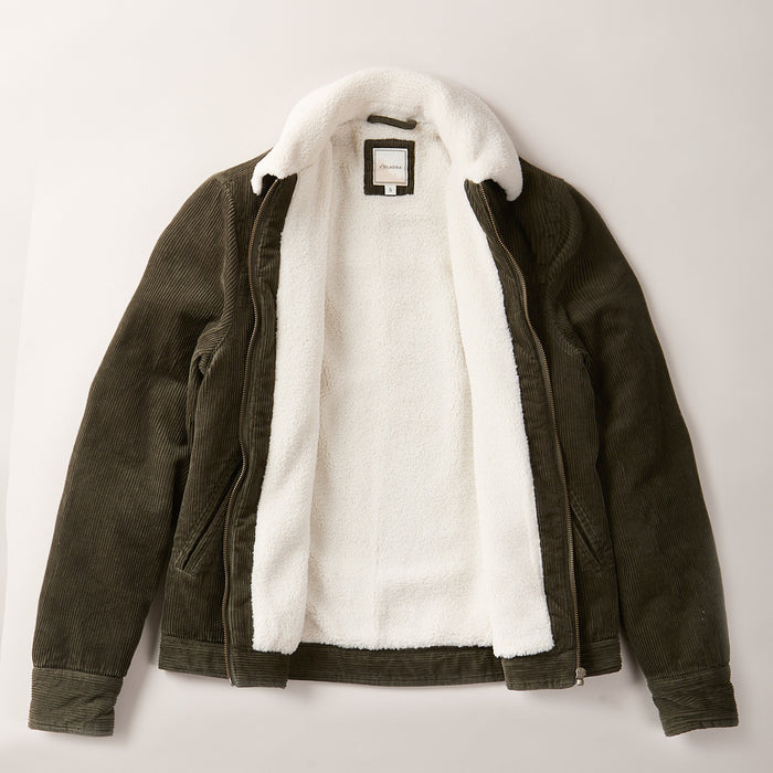 The Women's Stinson Jacket - Pine Green is a dark green cotton corduroy jacket with a soft sherpa lining throughout and at the collar, shown open and laid flat on a light background for ultimate comfort.