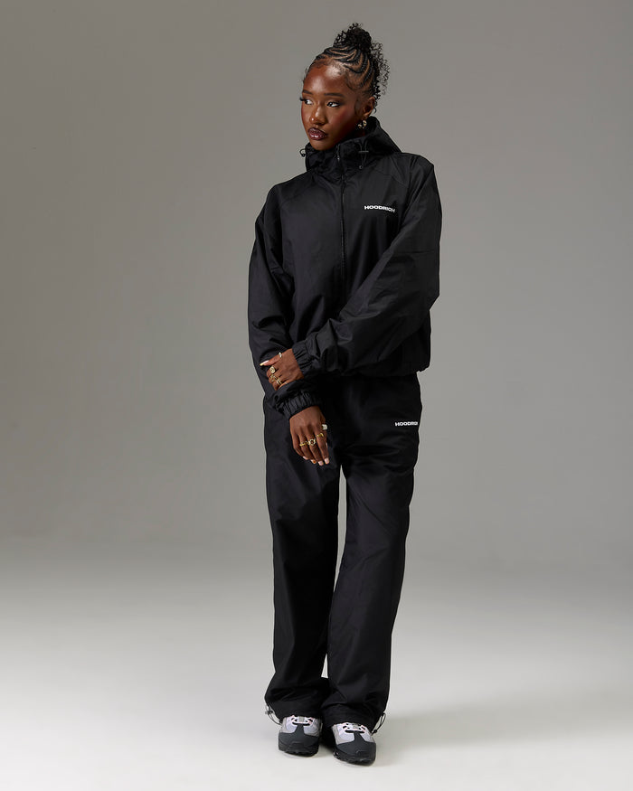 Displays a model wearing the Black 'Hoodrich' branded women's The Winner's Circle Ripstop Woven Full Tracksuit