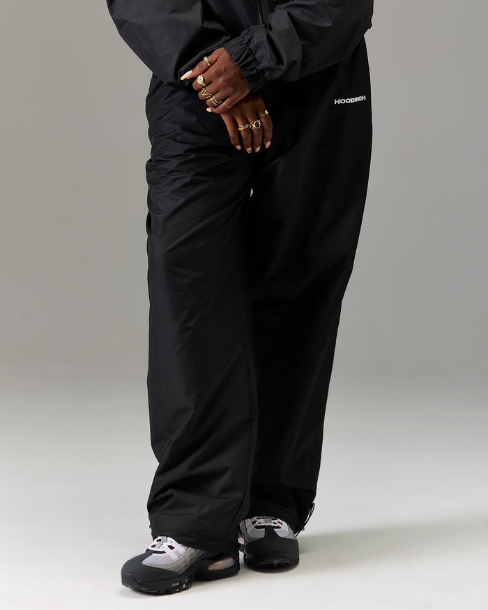Displays a model wearing the Black 'Hoodrich' branded women's The Winner's Circle Ripstop Woven Full Tracksuit