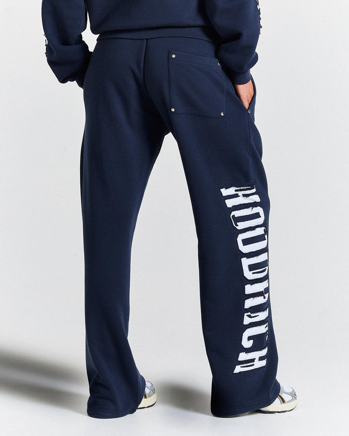 Navy blue sweatpants with 'Hoodrich' branding on a light gray background