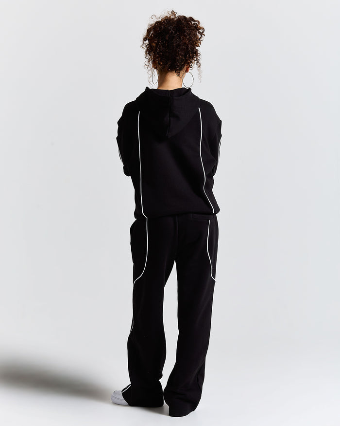 Person wearing a black tracksuit with white stripes on a light gray background