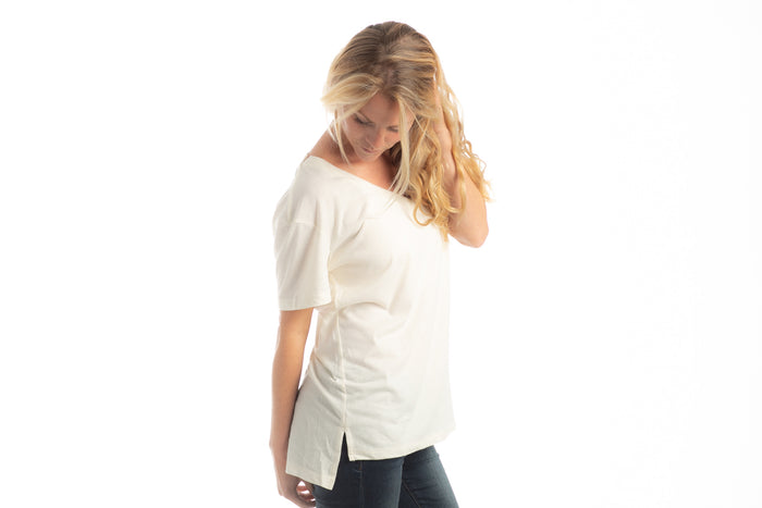 Blonde woman wears Pladra Women's V-Neck Tri-Blend Tee in Marshmallow White Heather, looking down against white backdrop.