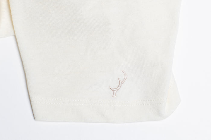 Close-up of Pladra Women’s V-Neck Tri-Blend Tee in Marshmallow White Heather with subtle hem embroidery.