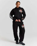 Person wearing a black hoodie and pants with floral designs on a white background