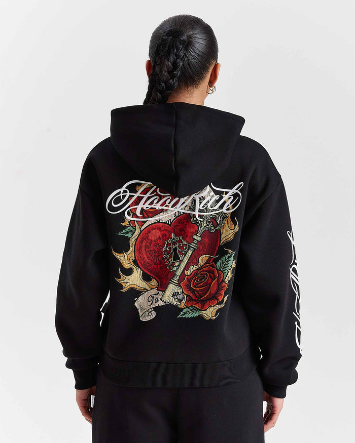 Person wearing a black hoodie with intricate designs and text on the back against a white background