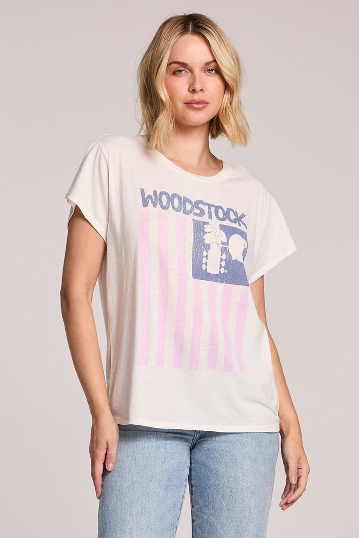Front view of a woman wearing the Chaser Woodstock American Flag Tee on a neutral background with one hand on her hip