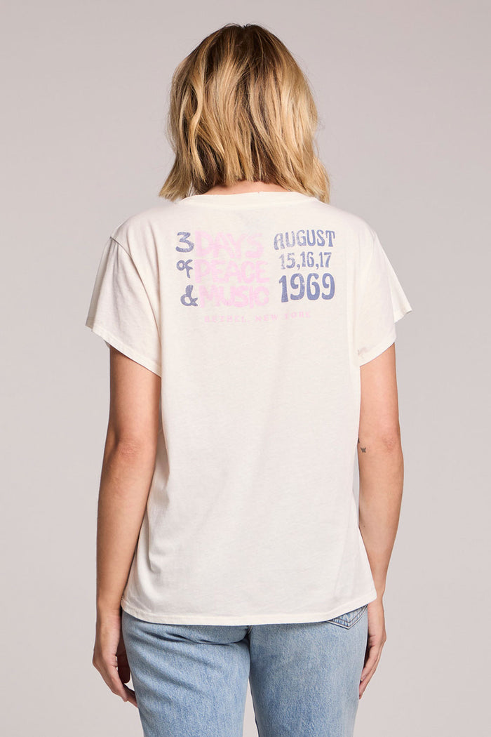Back view of a woman wearing the Chaser Woodstock American Flag Tee on a neutral background