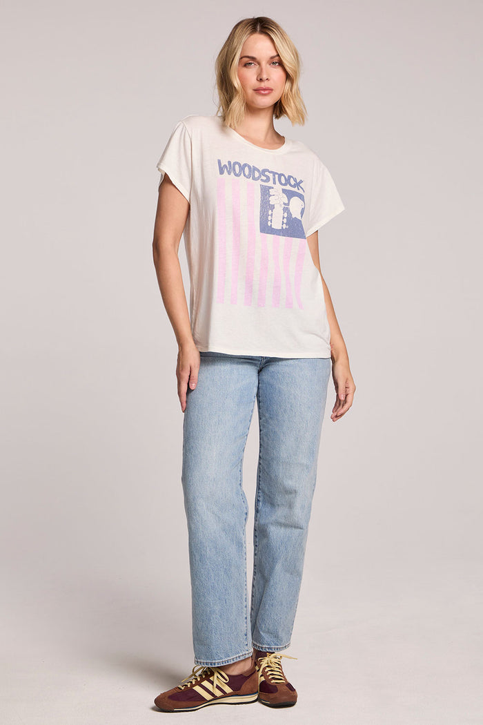 Full body front iew of a woman wearing the Chaser Woodstock American Flag Tee and jeans on a neutral background