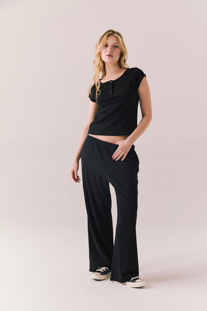 Full body of model in black henley tee and matching bottoms.