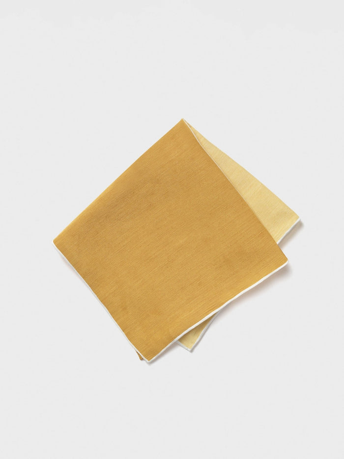 Mustard yellow pocket square folded diagonally, pale yellow underside visible.