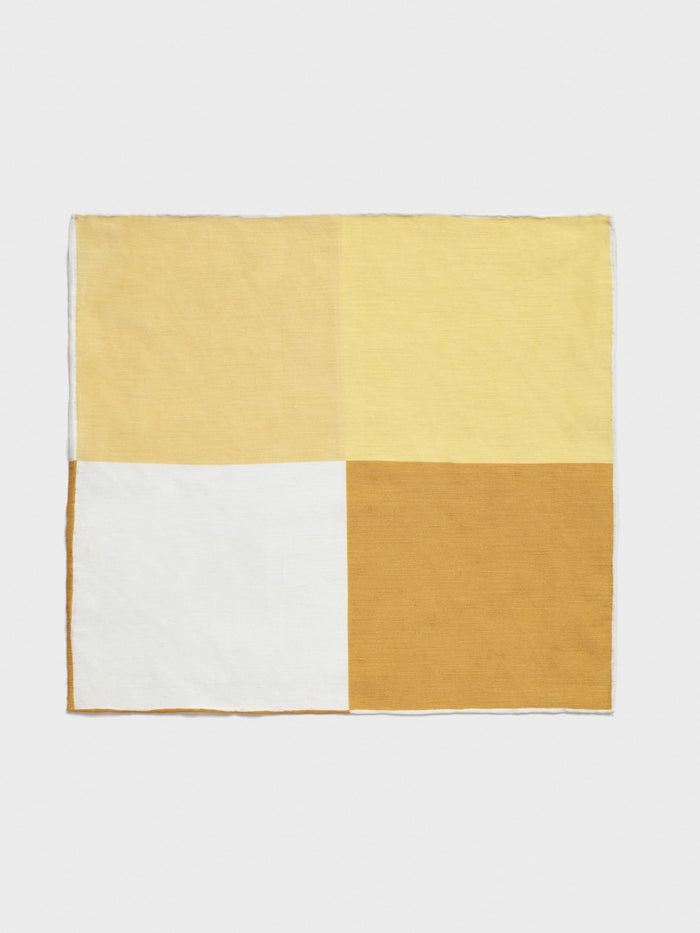 Pocket square with four color quadrants: mustard, pale yellow, white, and dark gold, flat.