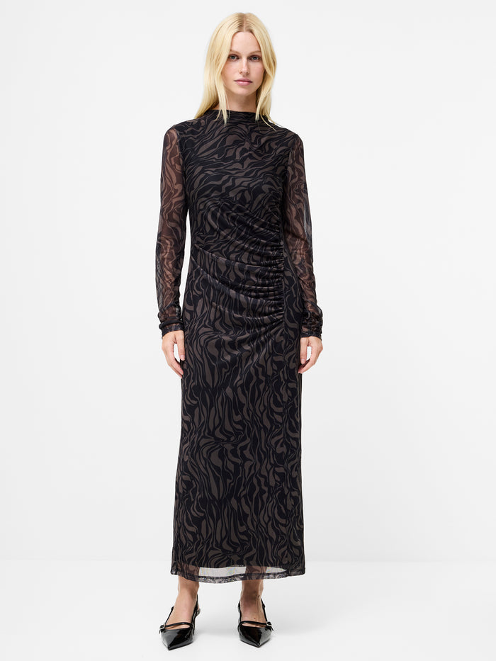 A woman wearing a  black maxi dress with an abstract print, semi sheer long sleeves and a mock neckline.