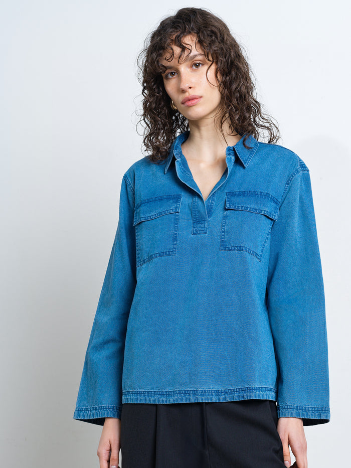 Woman wearing a long sleeve blue denim shirt with pocket detailing